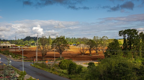 Clearing the Lot construction site dirt off of Kuebler blvd in Salem, Oregon showing the streets, dirt, blue sky with clouds, and trees